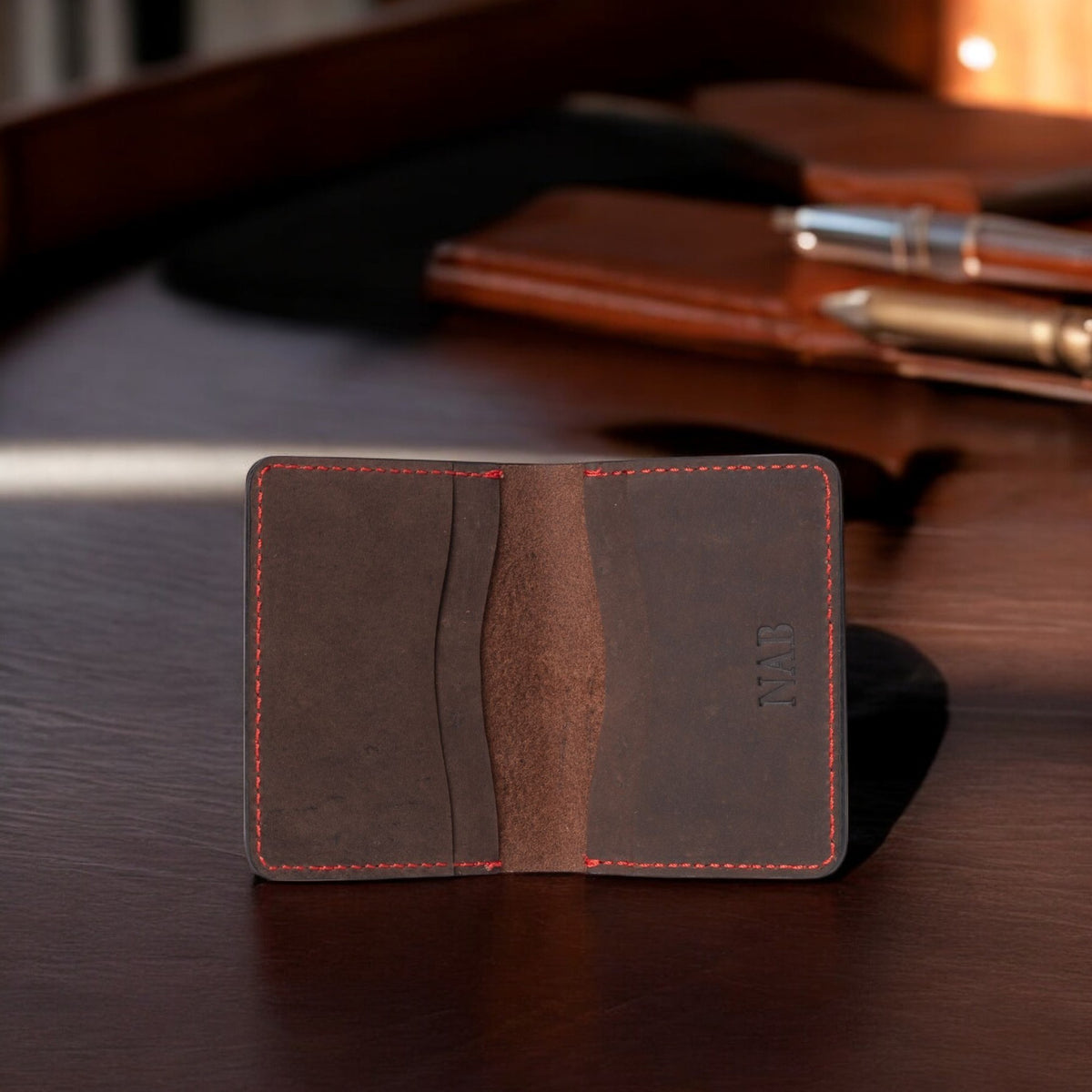 Brown full-grain leather card holder with red hand stitching