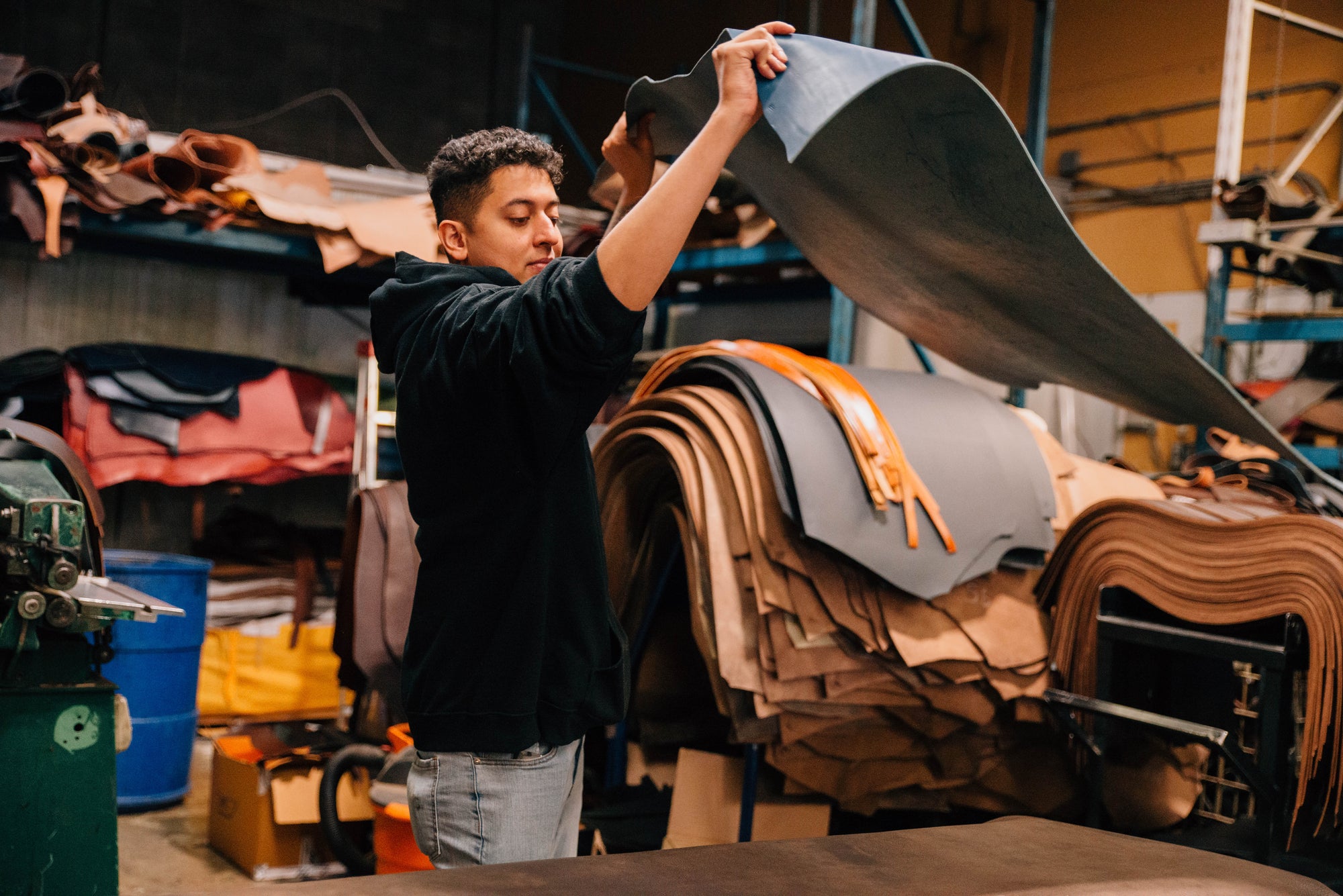Hands finishing the edge of a full-grain leather belt at the workbench