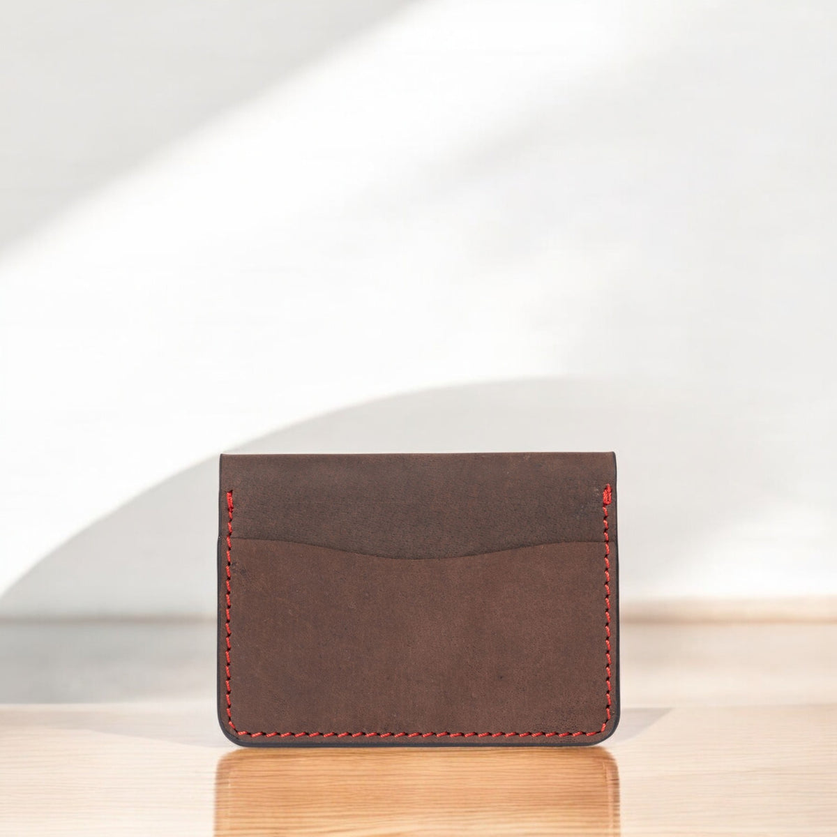 Brown full-grain leather card holder with red hand stitching
